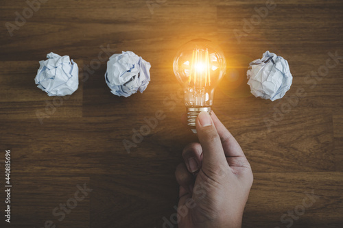 Hand choose light bulb and crumpled office paper. Concept of inspiration creative idea thinking and future technology innovation photo