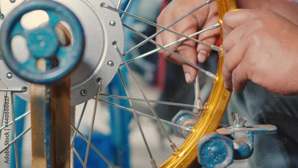 Technician man working motorcycle wheel has spokes weave up on mechanic