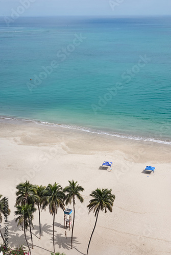 Aerial view of the beach with tents, palm trees and the lifeguard tower. Vertical photo