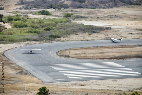 Two airplanes on the runway in the middle of the field.
