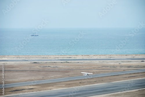 Light aircraft taking off on the runway next to the pacific ocean.