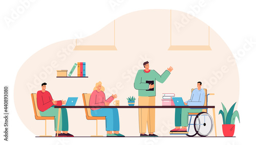 Male student in wheelchair attending lesson at school. Group of people having conversation, working together. Teacher standing and explaining new material. Inclusion, meeting, education concept