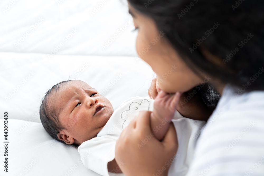Newborn baby and young mother. Smiling mom with African American newborn on bed. family, love, happy and new life concept Newborn baby and young mother. Smiling mom with African American newborn on bed. family, love, happy and new life concept