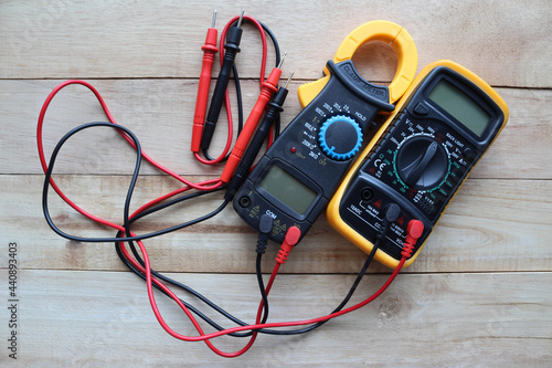 Cuadro en lienzo Digital multimeter, clamp-on meter with probes, electrical measuring instruments isolated on wooden background closeup