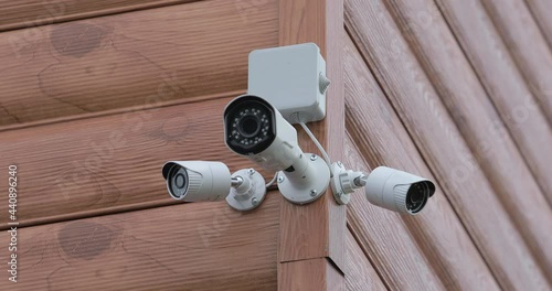 A video surveillance system consisting of three cameras. Video cameras are located on the corner of the building. Power is supplied from a junction box that is located nearby.