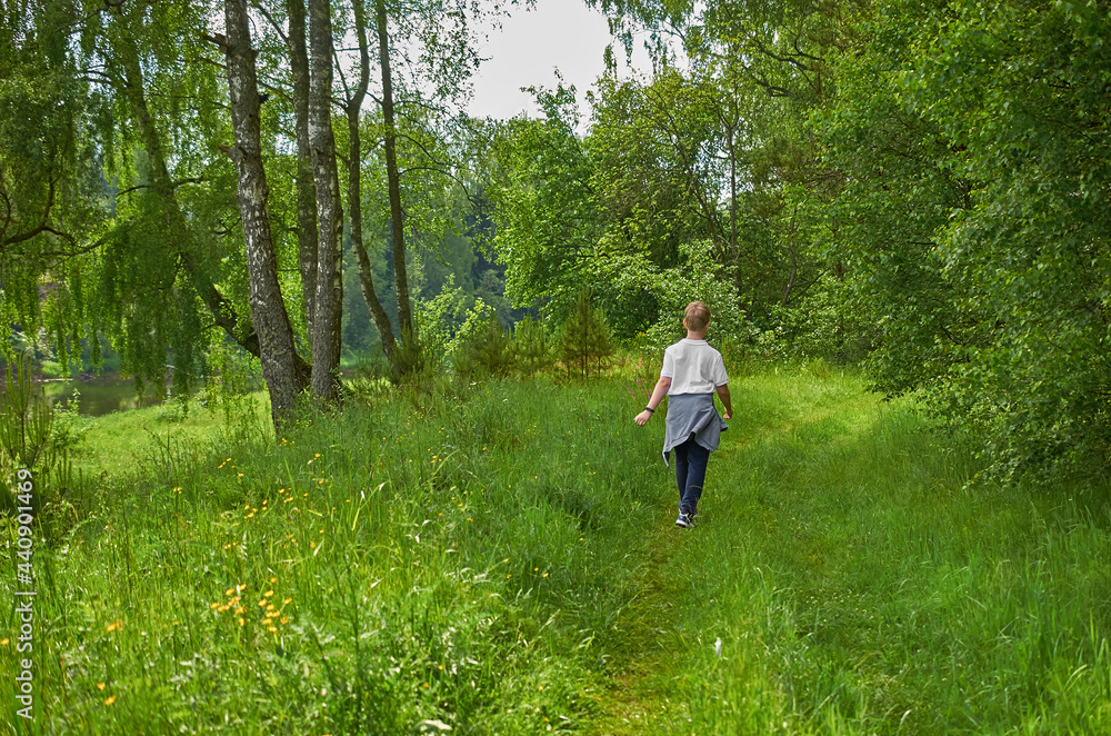 A European teenager walks along a path in the forest A European teenager walks along a path in the forest