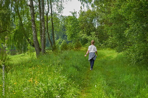 A European teenager walks along a path in the forest