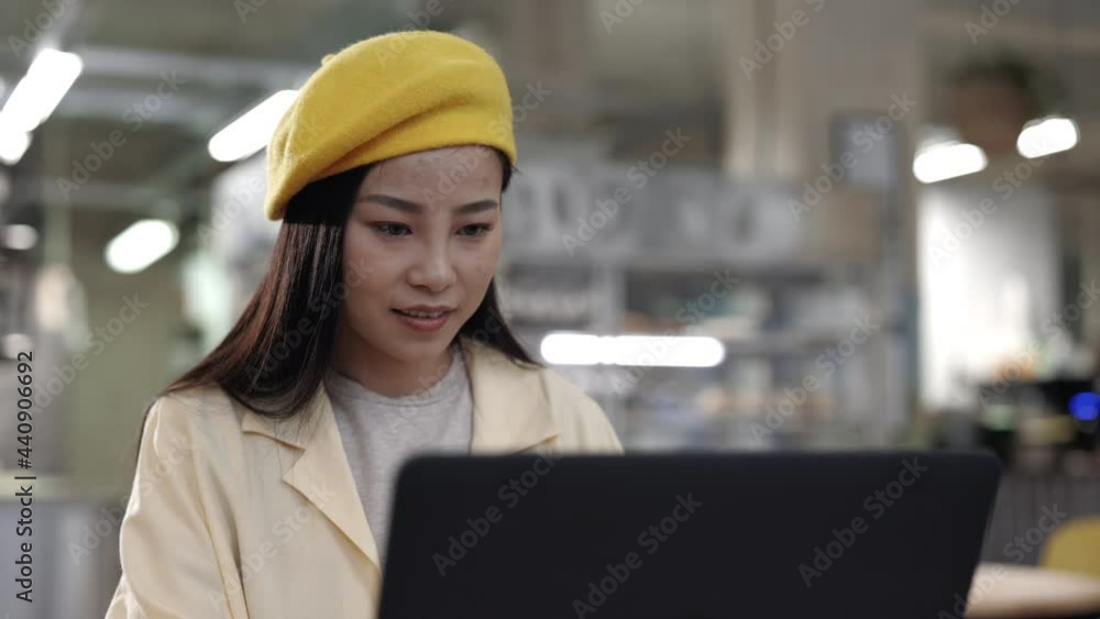Asian woman working on laptop while sitting at cafe Asian woman working on laptop while sitting at cafe