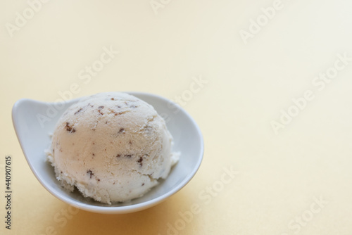 selbstgemachtes Stracciatella Eis mit Ahornsirup, Schokolade mit Kokosblütenzucker, Hintergrund gelb