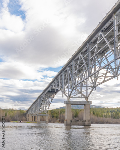 Johnsons Crossing Bridge over Teslin River in northern Canada during spring  summer time with steel beams running above and blue sky in background along the Alaska Highway  Yukon Territory.