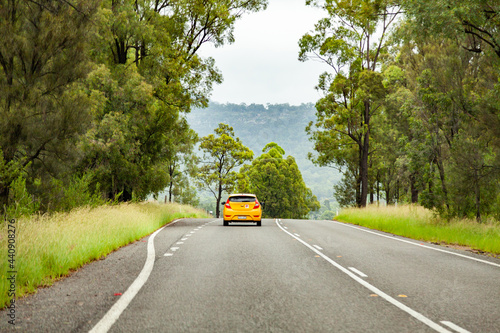 Yellow car with p plate driving down country road photo