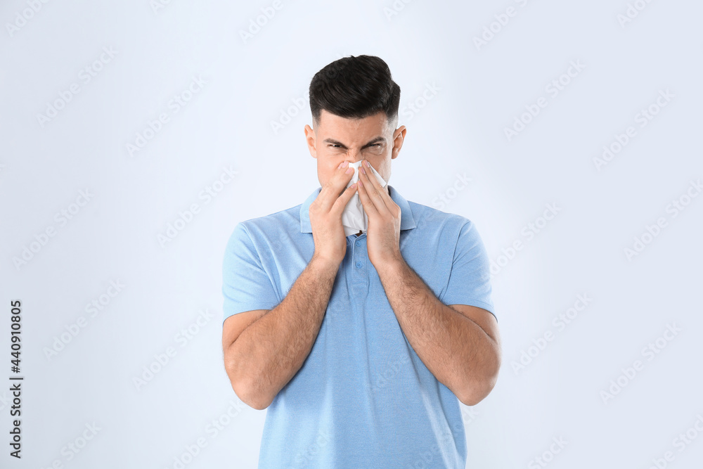 Man with tissue suffering from runny nose on white background Man with tissue suffering from runny nose on white background
