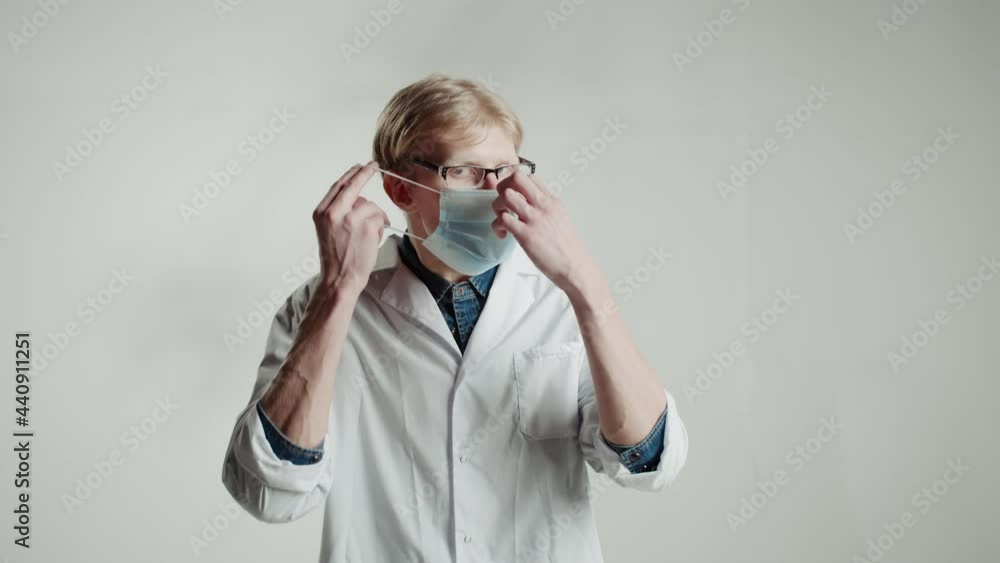 Caucasian man doctor putting on medical mask in glasses, looking in camera on white backgrounds. Student of medical university portrait, young blonde nurse male. Caucasian man doctor putting on medical mask in glasses, looking in camera on white backgrounds. Student of medical university portrait, young blonde nurse male.