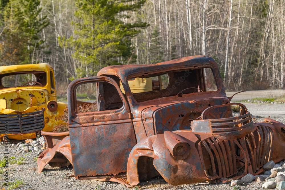 Abandoned rusty 1940s style truck sitting in the wilderness of Yukon Territory during summer time with yellow, rust colored theme and boreal forest in background. Abandoned rusty 1940s style truck sitting in the wilderness of Yukon Territory during summer time with yellow, rust colored theme and boreal forest in background.