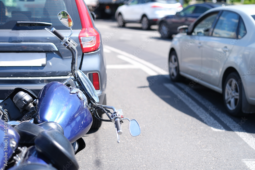 Blue motorcycle lying in front of car on road closeup