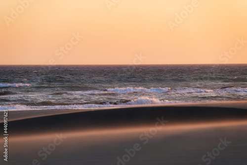 Sand dunes and seashore during sunset. Summer landscape in the desert. Hot we...