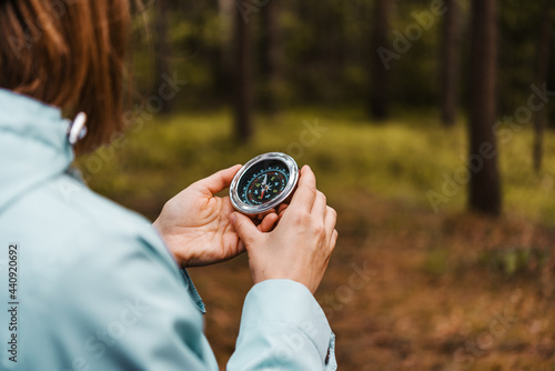 A women in blue coat holds a compass in hand and is guided by the area, autumn forest, walk,hiking