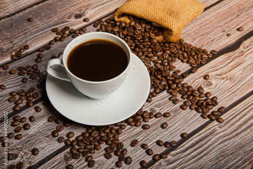 Fototapeta Naklejka Na Ścianę i Meble -  Cup of coffee and coffee beans on old wooden background