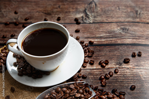 Cup of coffee and coffee beans on old wooden background