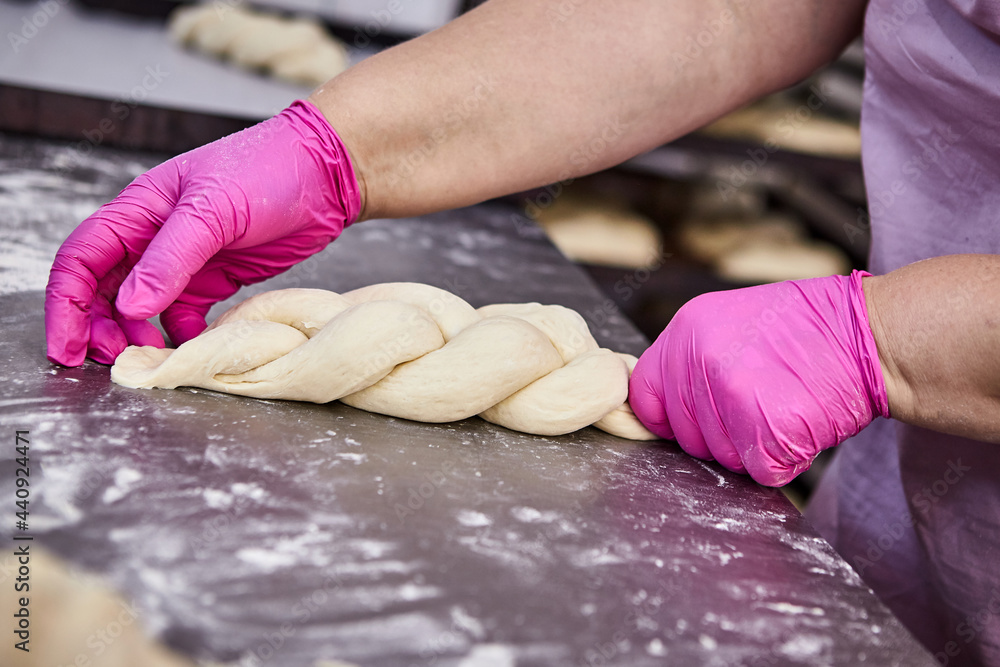 Bakers hands form dough for baking bread and put it into oven-tray at the manufacturing Bakers hands form dough for baking bread and put it into oven-tray at the manufacturing
