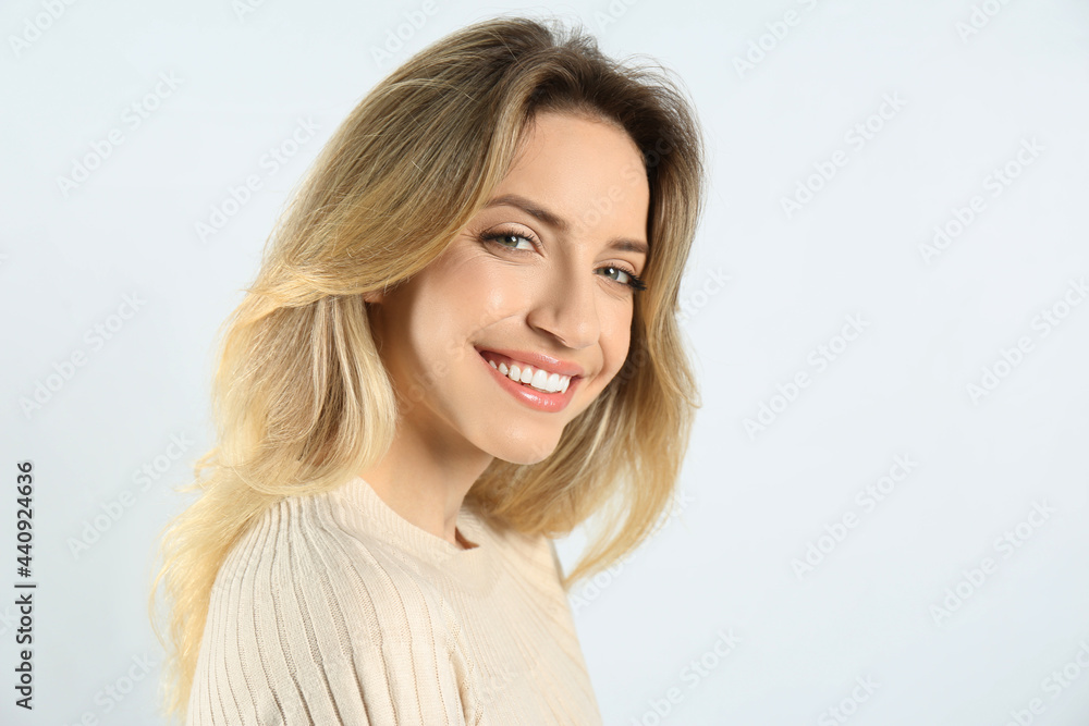 Portrait of happy young woman with beautiful blonde hair and charming smile on light background. Space for text Portrait of happy young woman with beautiful blonde hair and charming smile on light background. Space for text