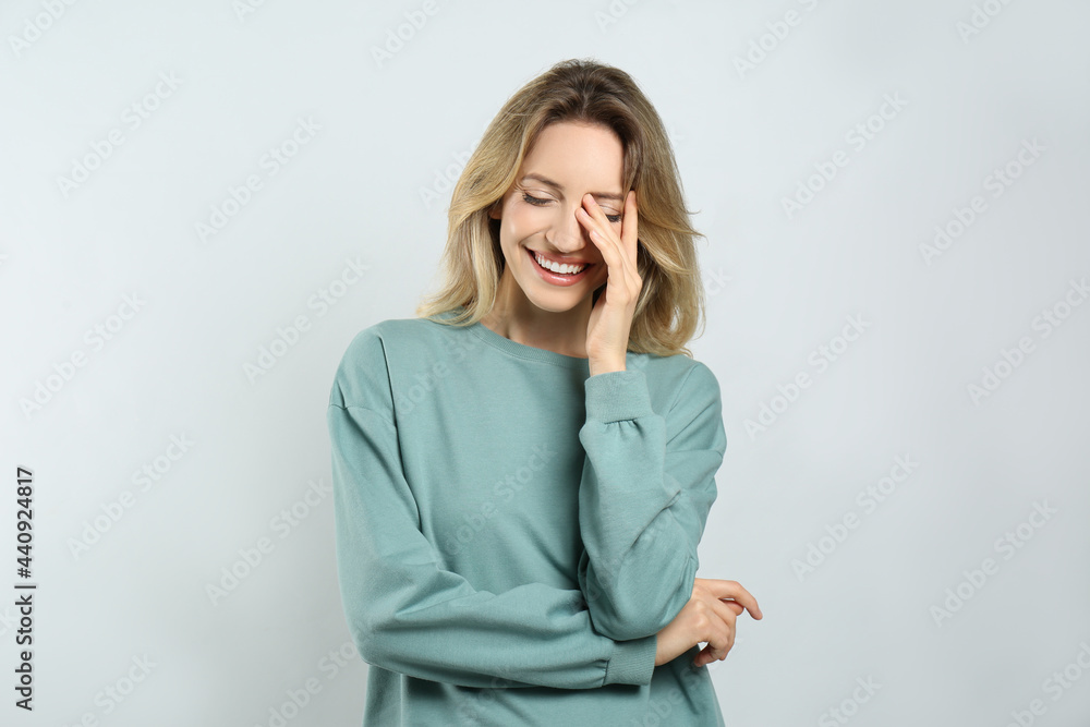 Portrait of happy young woman with beautiful blonde hair and charming smile on light background Portrait of happy young woman with beautiful blonde hair and charming smile on light background