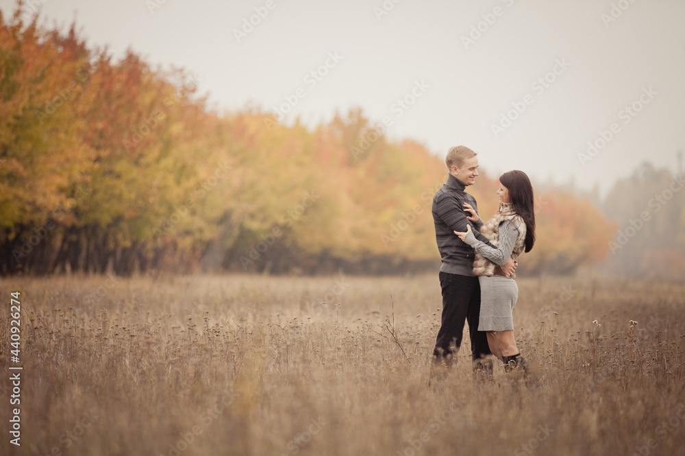 couple on autumn walk outdoors. Two lovers are hugging in autumn garden. Love and tender touch. Foggy cloudy day filled with the warmth of love. Beautiful autumn landscape for romantic date. couple on autumn walk outdoors. Two lovers are hugging in autumn garden. Love and tender touch. Foggy cloudy day filled with the warmth of love. Beautiful autumn landscape for romantic date.