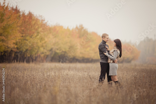 couple on autumn walk outdoors. Two lovers are hugging in autumn garden. Love and tender touch. Foggy cloudy day filled with the warmth of love. Beautiful autumn landscape for romantic date.  © Olga Mishyna