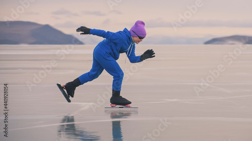 The child train on ice professional speed skating. The girl skates in the winter in sportswear, sport glasses, suit. Children speed skating short long track, kid sport. Outdoor slow motion.