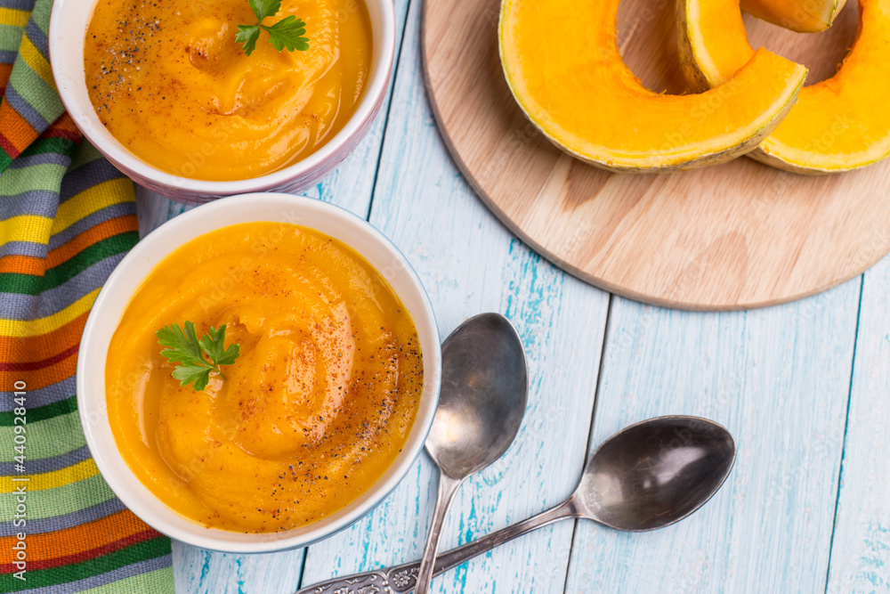 Traditional autumn pumpkin soup with bright masks on a blue background. Vegetarian delicious food. Traditional autumn pumpkin soup with bright masks on a blue background. Vegetarian delicious food.