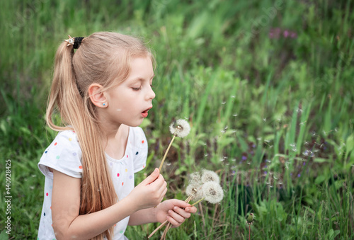 Little girl with white dandelions in her hands