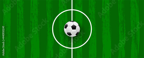 Green football field made of brush stroke with realistic soccer ball. Vector banner template for sport tournaments and competitions