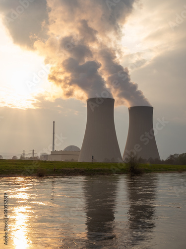 Nuclear power plant against sky by the river at sunset