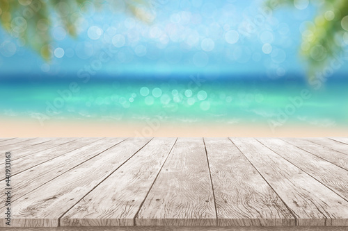 wooden table top summer time tropical blurry seascape with blurry palm leaves and bokeh against blue sky Summer beach Advertisment display background concept