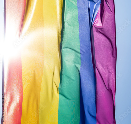 Rainbow flag in sunshine against blue sky © wlad074