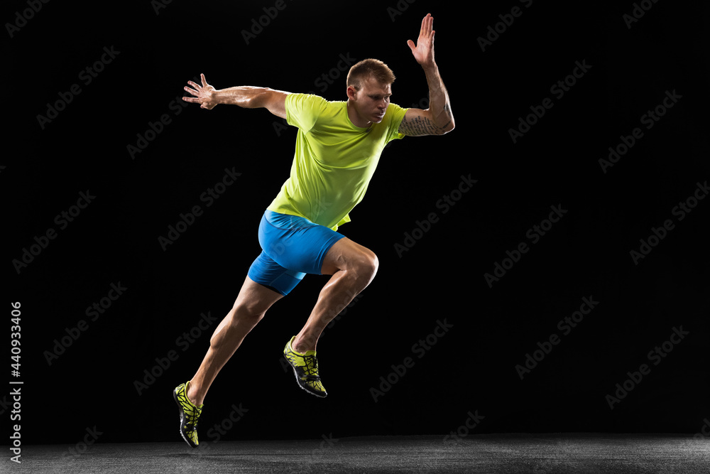 Caucasian professional male athlete, runner training isolated on black studio background. Muscular, sportive man. Concept of action, motion, youth, healthy lifestyle. Copyspace for ad.