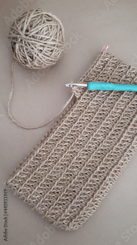 Top view of a crotchet fabric with a needle and a roll of yarn