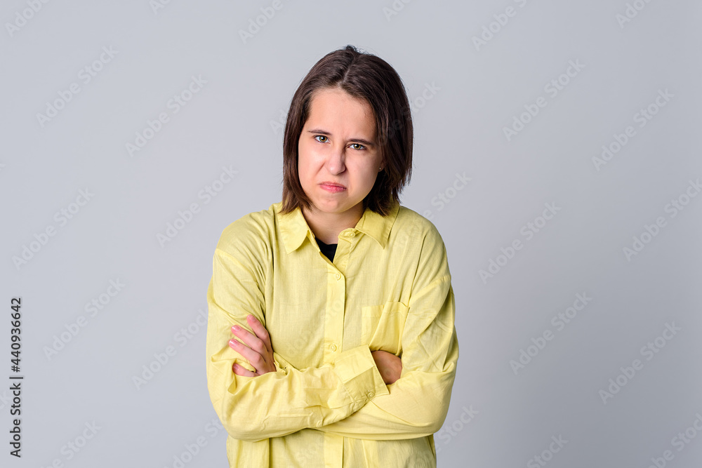 Angry sad teen girl with crossed arms isolated on gray background Angry sad teen girl with crossed arms isolated on gray background