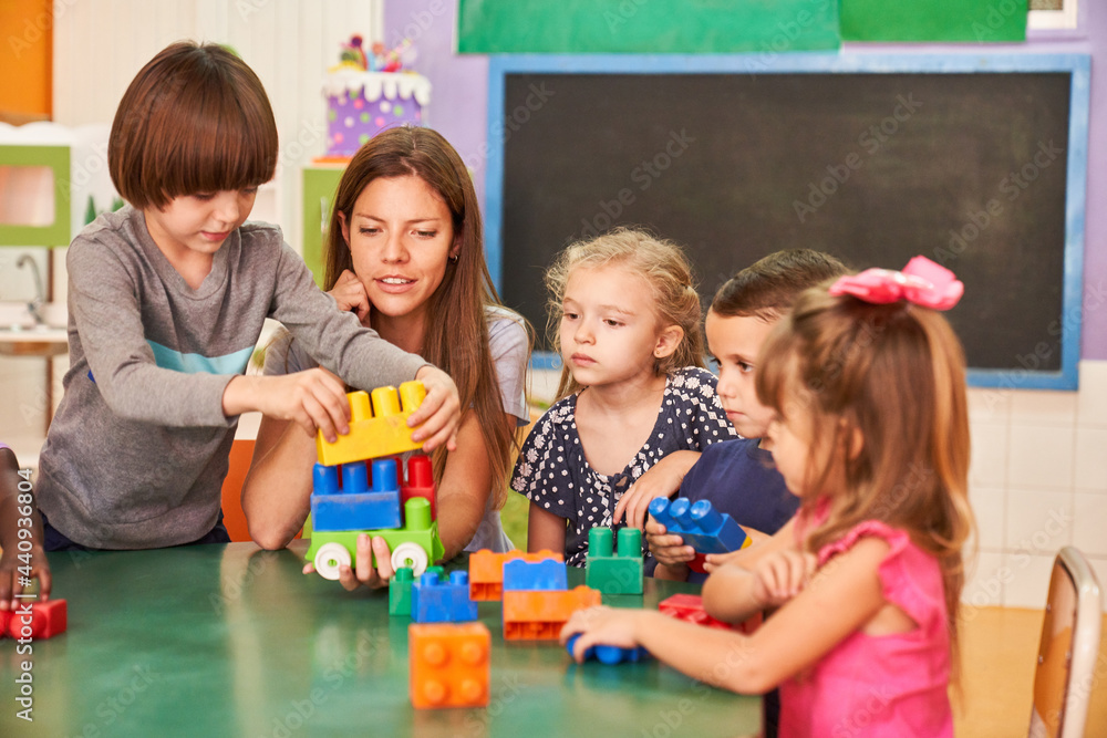 Children and educator play together with building blocks Stock Photo