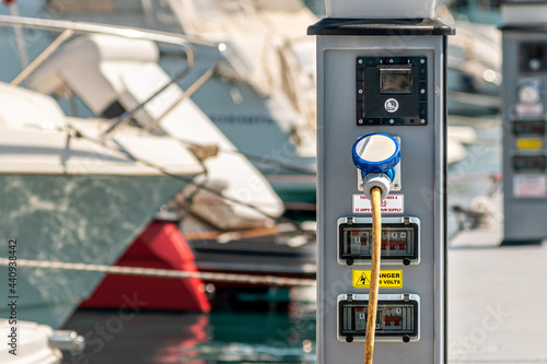 Electrical power sockets bollard on pier near sea coast. Charging station for boats in Mediterranean. Electrical outlets to charge ships in harbor.