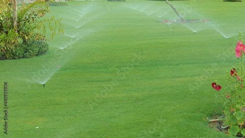 Rotating automatic sprinkler over lawn, modern irrigation device or system to watering garden over green grass maintenance service. Gardening service. 4K