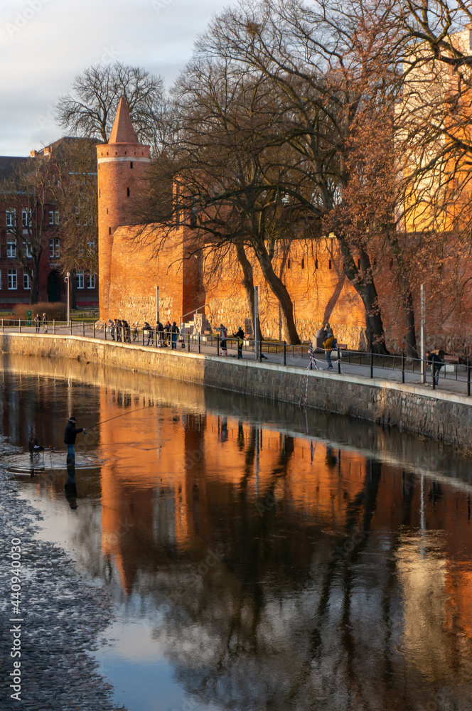 Ina River at sunset. Medieval town walls, Powder Tower (or Prison Tower), embankment. Goleniow, Poland.