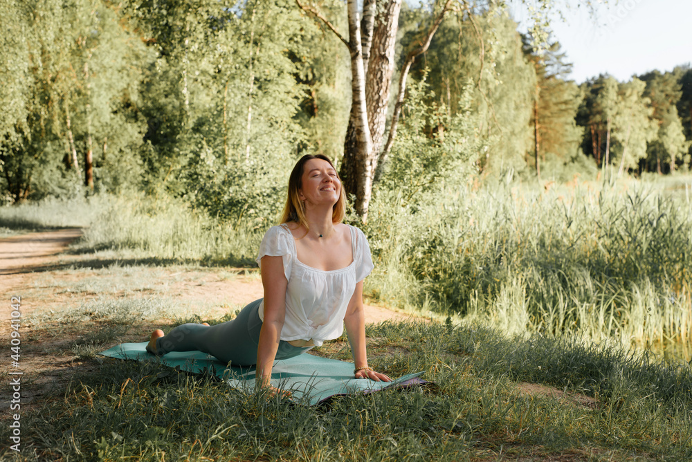 custom made wallpaper toronto digitalYoung fitness woman smiling, practicing yoga in nature. Happy sportive girl performing yoga asana on sports mat, summer sunset. Outdoor yoga. Active healthy lifestyle concept. Urdhva Mukha Svanasana