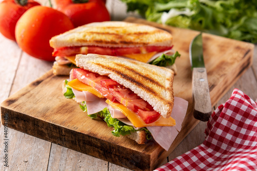 Sandwich with tomato,lettuce,ham and cheese on wooden table	