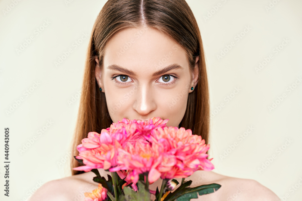 Portrait of beautiful young woman with flowers on studio background