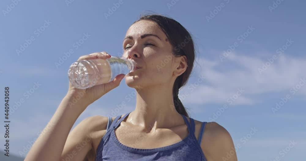 Slow motion shot of sporty trail running woman while drinking water and resting from intense jogging exercise. Slow motion shot of sporty trail running woman while drinking water and resting from intense jogging exercise.