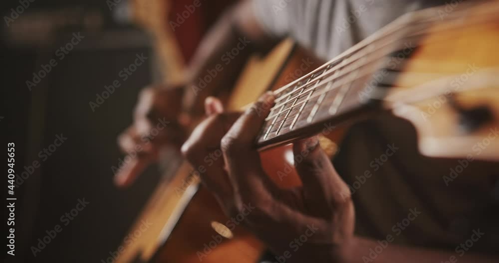 Young African-American man plays guitar in semi-dark studio Young African-American man plays guitar in semi-dark studio