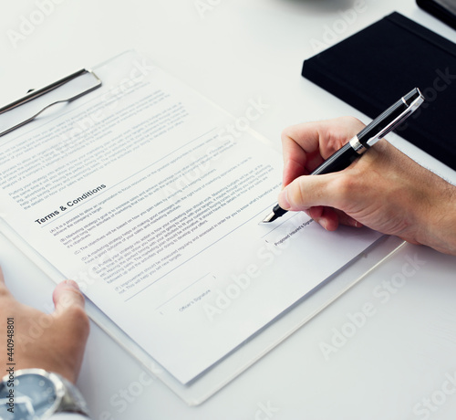 Closeup of hand signing paper workspace photo