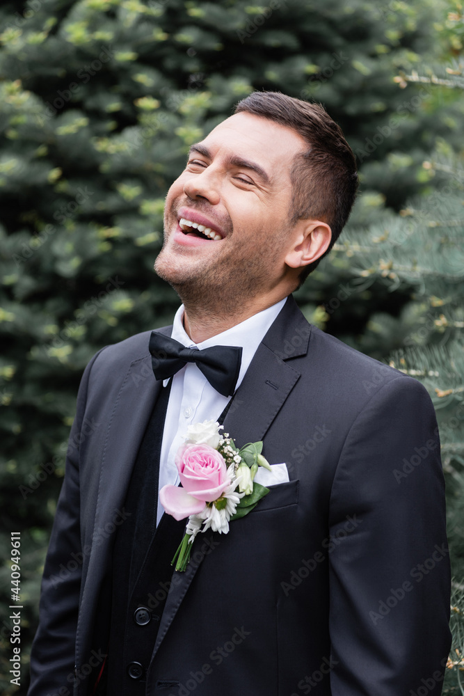 Excited groom in suit laughing in park Excited groom in suit laughing in park