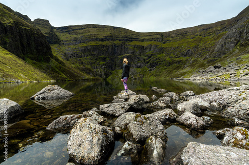 Woman standing on stones at Coumshingaun Lake Ireland